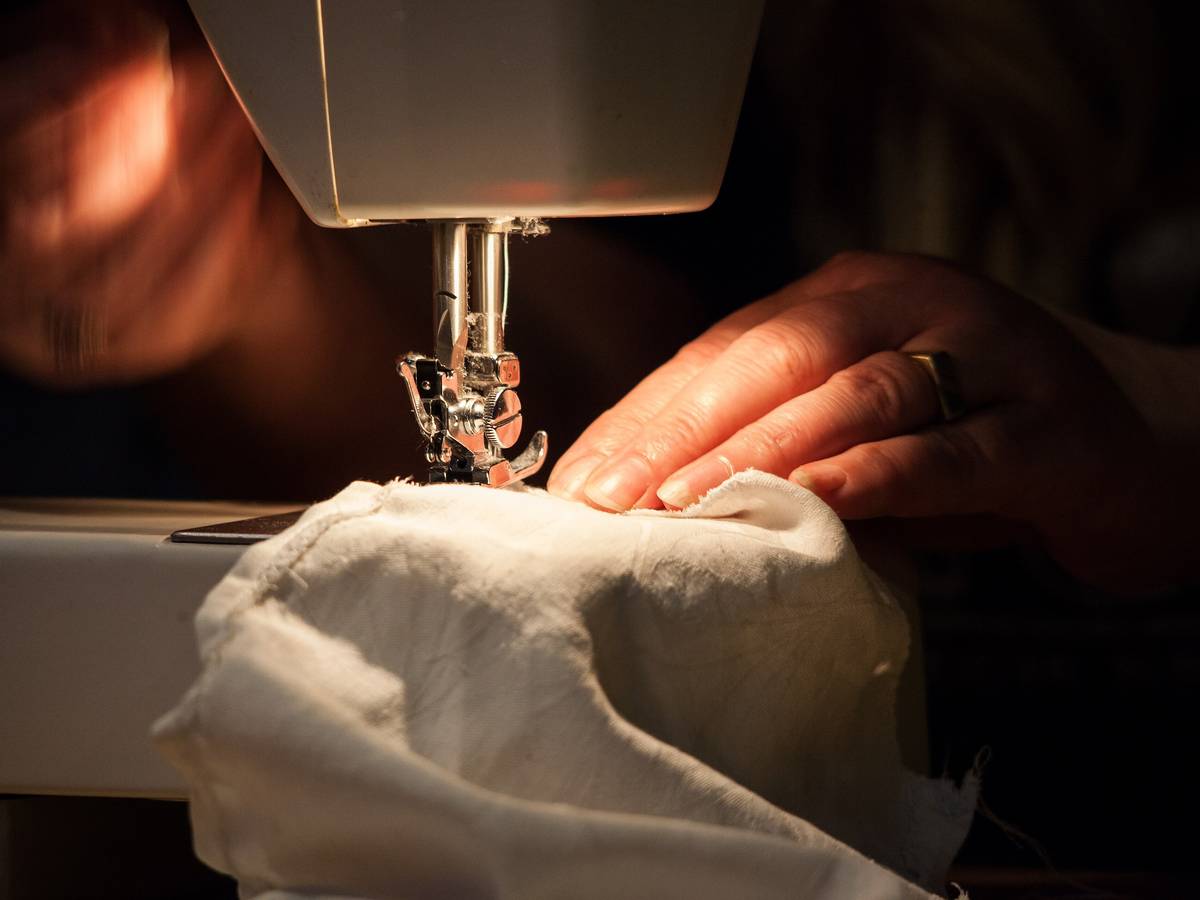 Hands guiding fabric through a sewing machine